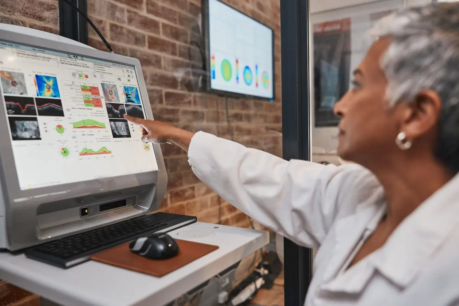 An optometrist reviewing retinal imaging on a clinical workstation