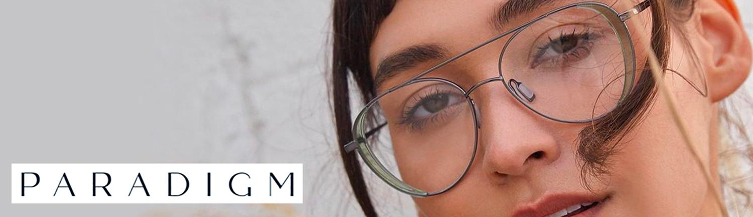 Woman wearing round wire-frame glasses, beside the Paradigm wordmark