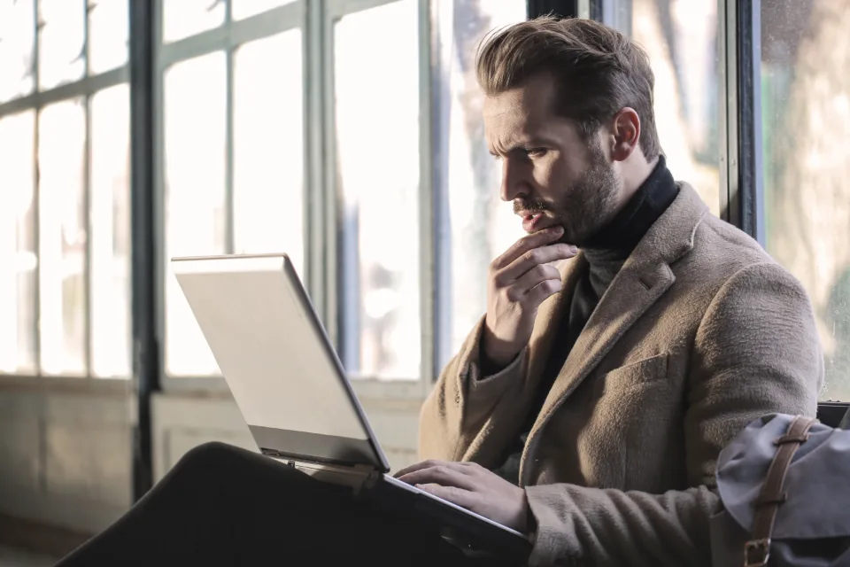 Man in suit working on laptop while sitting by large window