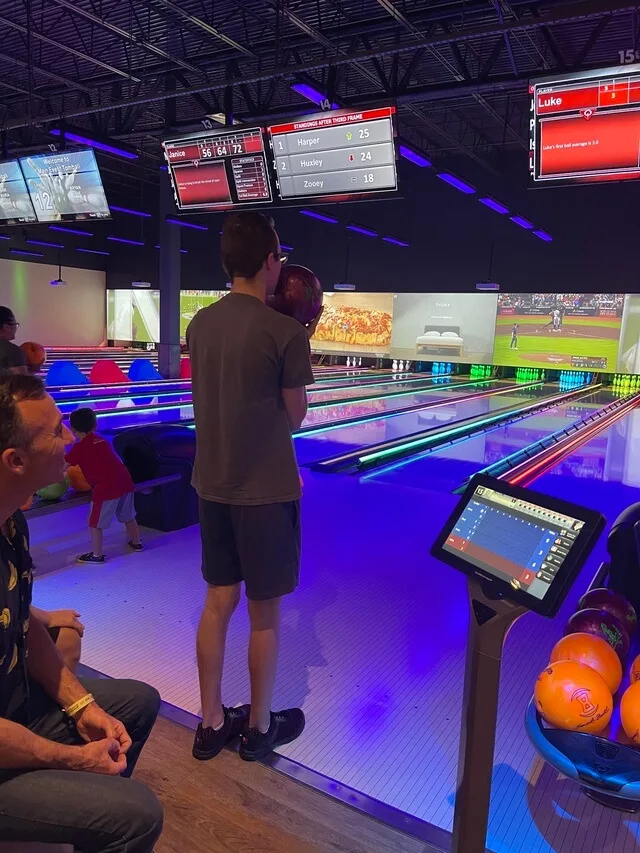 Young man holding bowling ball ready to play under neon lights
