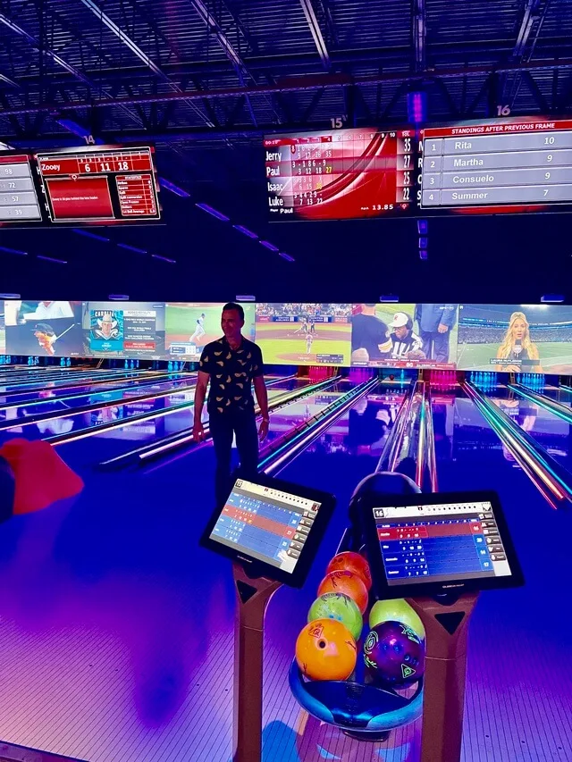 Man standing at bowling alley lanes with colorful bowling balls