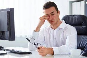 man rubbing eyes