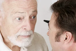 Eye doctor examining elderly man during routine checkup