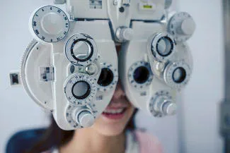 Patient receiving vision exam using phoropter eye machine