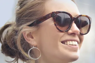 Smiling woman wearing stylish designer sunglasses outdoors