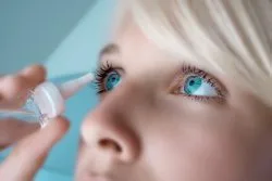 Woman applying eye drops for dryness relief or eye care